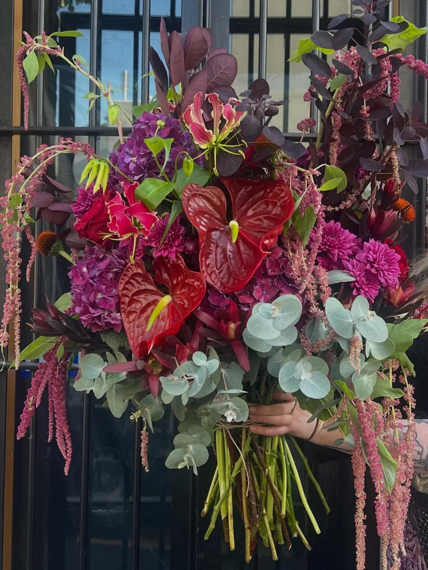 Dark Romance — jewel-toned hand-tied bouquet held against the Smith Street shopfront